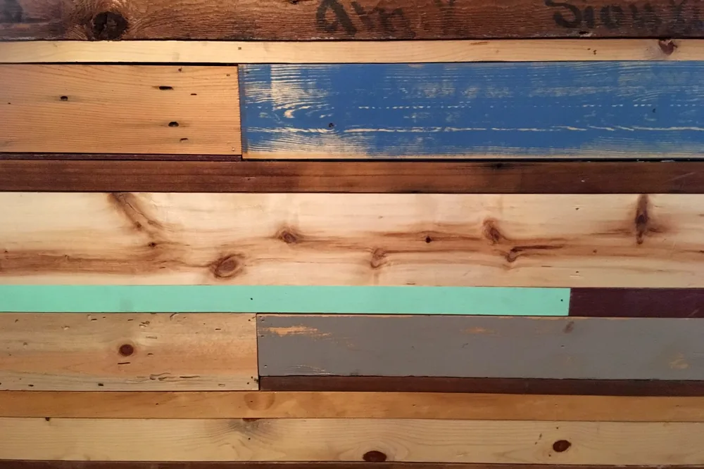 The dining room wall at M.B. Haskett, built from salvaged boards, some painted blue, mint and maroon