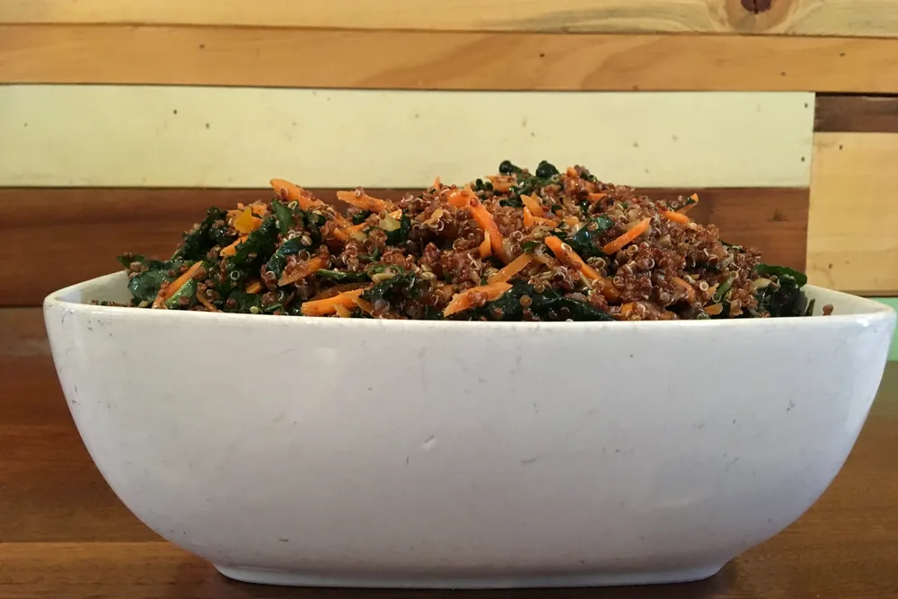 A bowl of red quinoa salad with kale and carrot